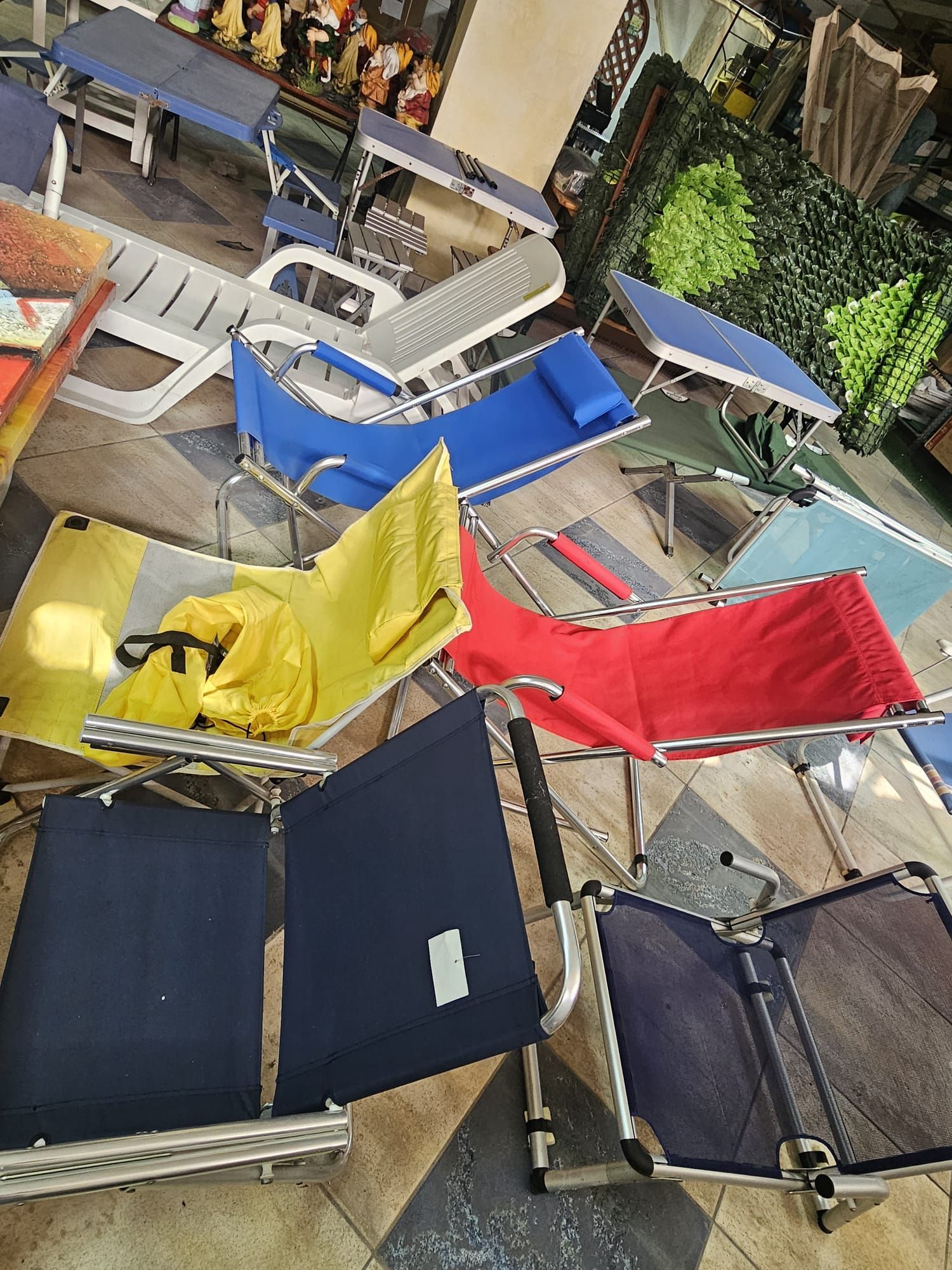 Un mucchio di sedie pieghevoli sono appoggiate sul pavimento in una stanza.