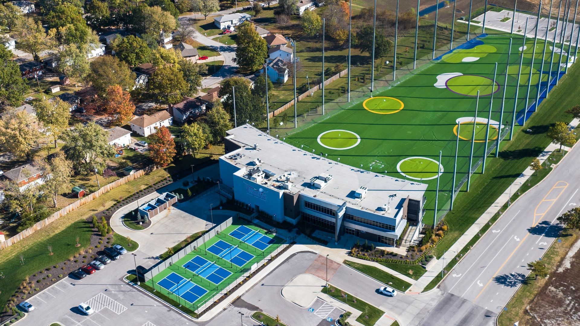An aerial view of a golf course with a large building in the background.
