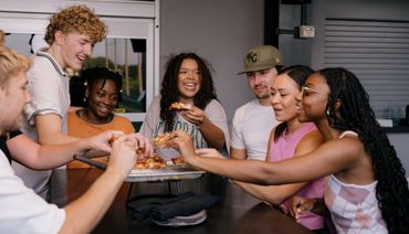 A group of people are sitting around a table eating pizza.