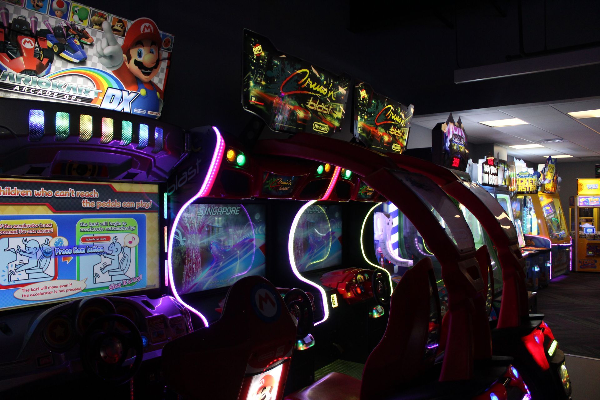 Arcade with illuminated racing game consoles featuring Mario.
