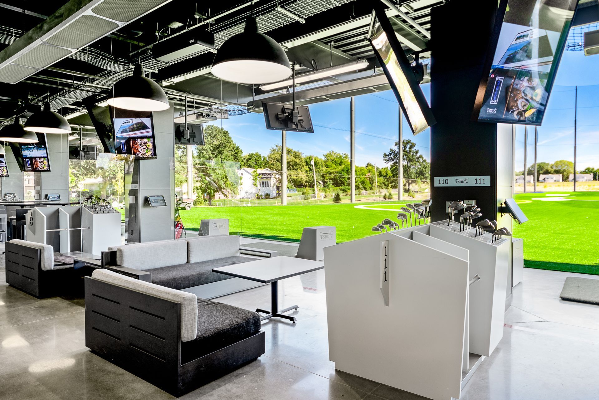 A living room with a couch , table , televisions and a golf course in the background.