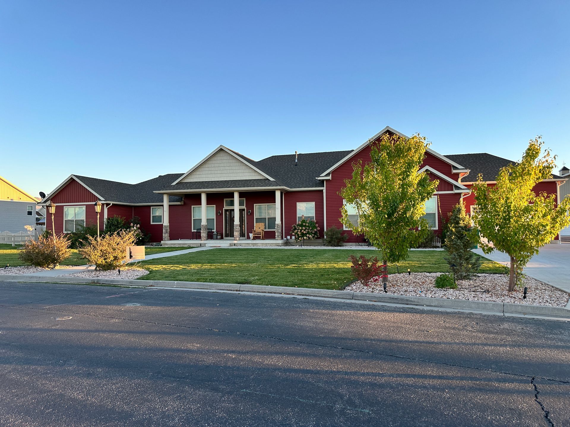 A large red house with a black roof is sitting on top of a lush green lawn.