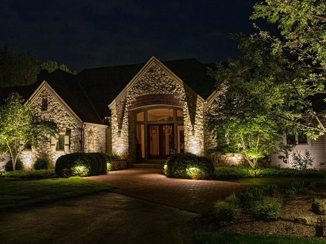 The front of a large house is lit up at night.