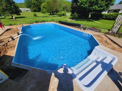 A large blue swimming pool is being built in a backyard.