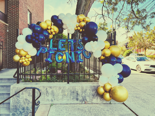 “Let’s Go!” balloon display on a building entrance with blue, white, and gold balloons