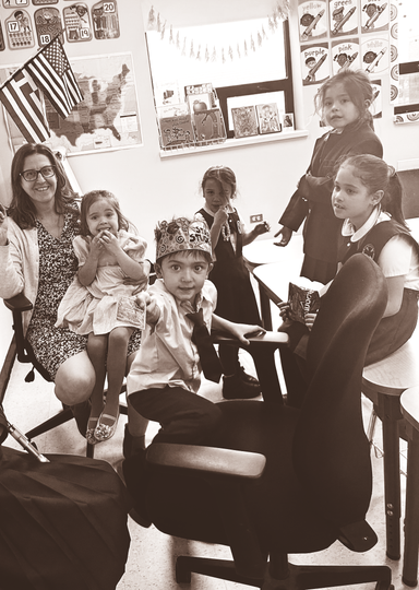 Group of people seated in a classroom, smiling at the camera amid colorful wall art.
