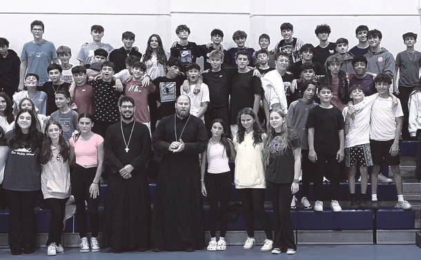 Large group posing on bleachers in a gym, with several students and adults arranged in rows.