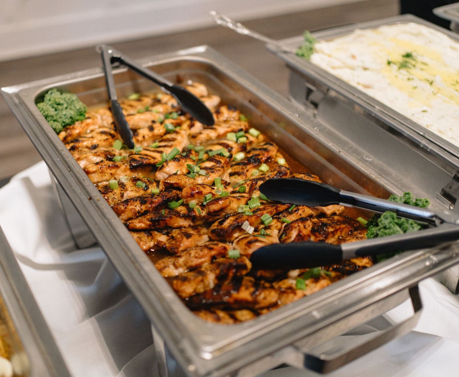 A large white house sits on the shore of a lake