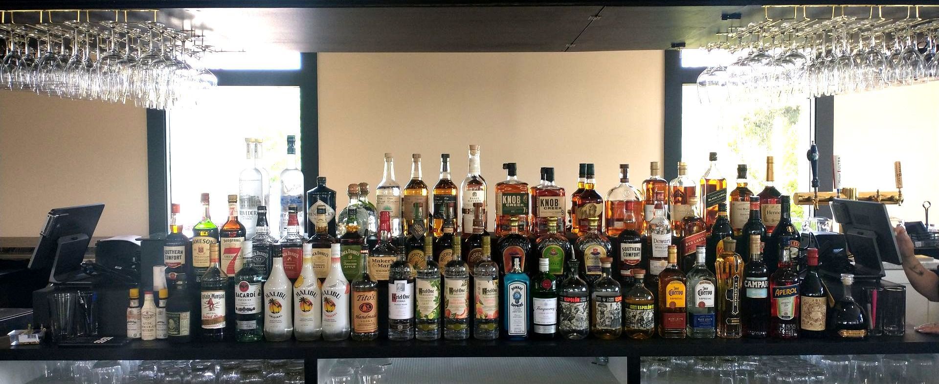 A bar filled with lots of bottles of liquor and wine glasses.