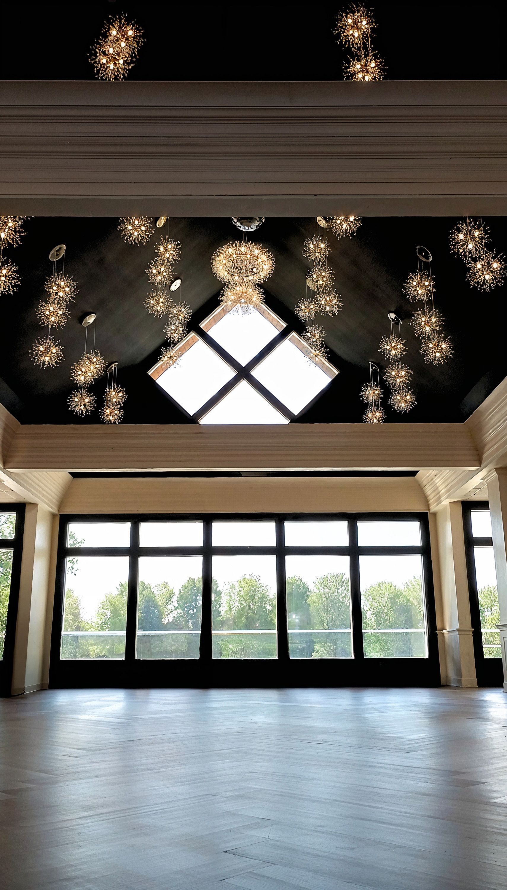 A large empty room with a lot of windows and a chandelier hanging from the ceiling.