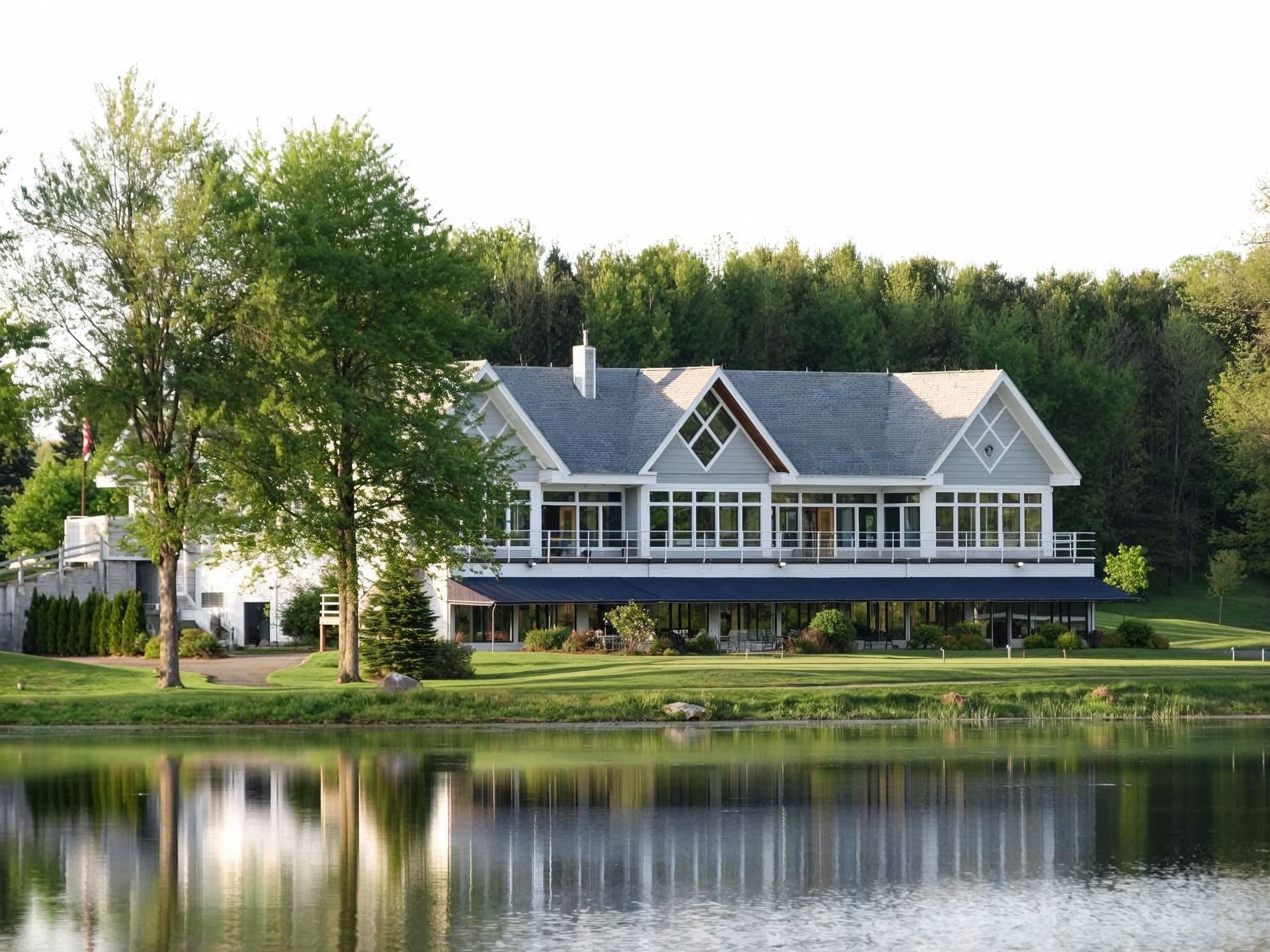 A large house sits on the shore of a lake surrounded by trees.
