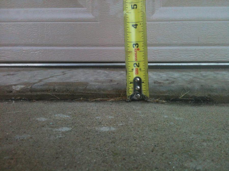 A yellow tape measure measures the height of a garage door 