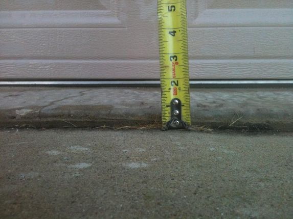 A yellow tape measure measures the height of a garage door 