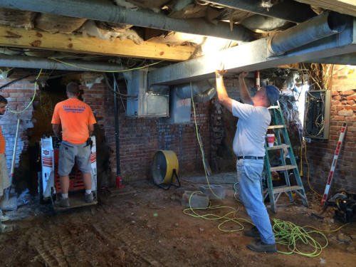 A group of men are working in a basement | Jack-A-Slab Construction