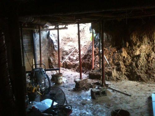 A basement with a hole in the wall and a fan.
