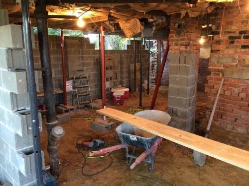 Basement under construction with concrete block walls, support jacks, and a wheelbarrow.