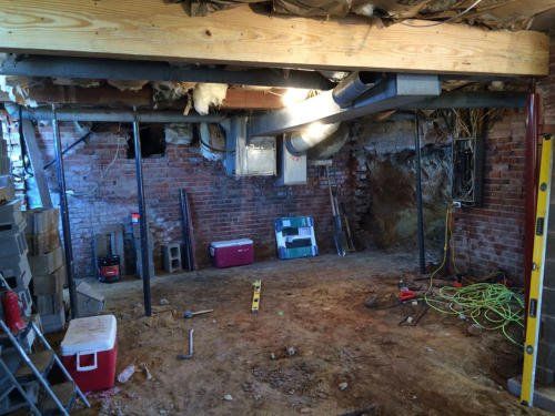 A basement with a brick wall and a wooden beam.