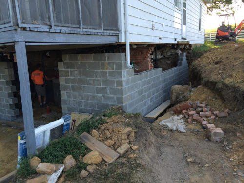 A brick wall is being built around a house.