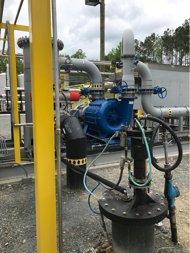 A blue pump is sitting on top of a black pipe.