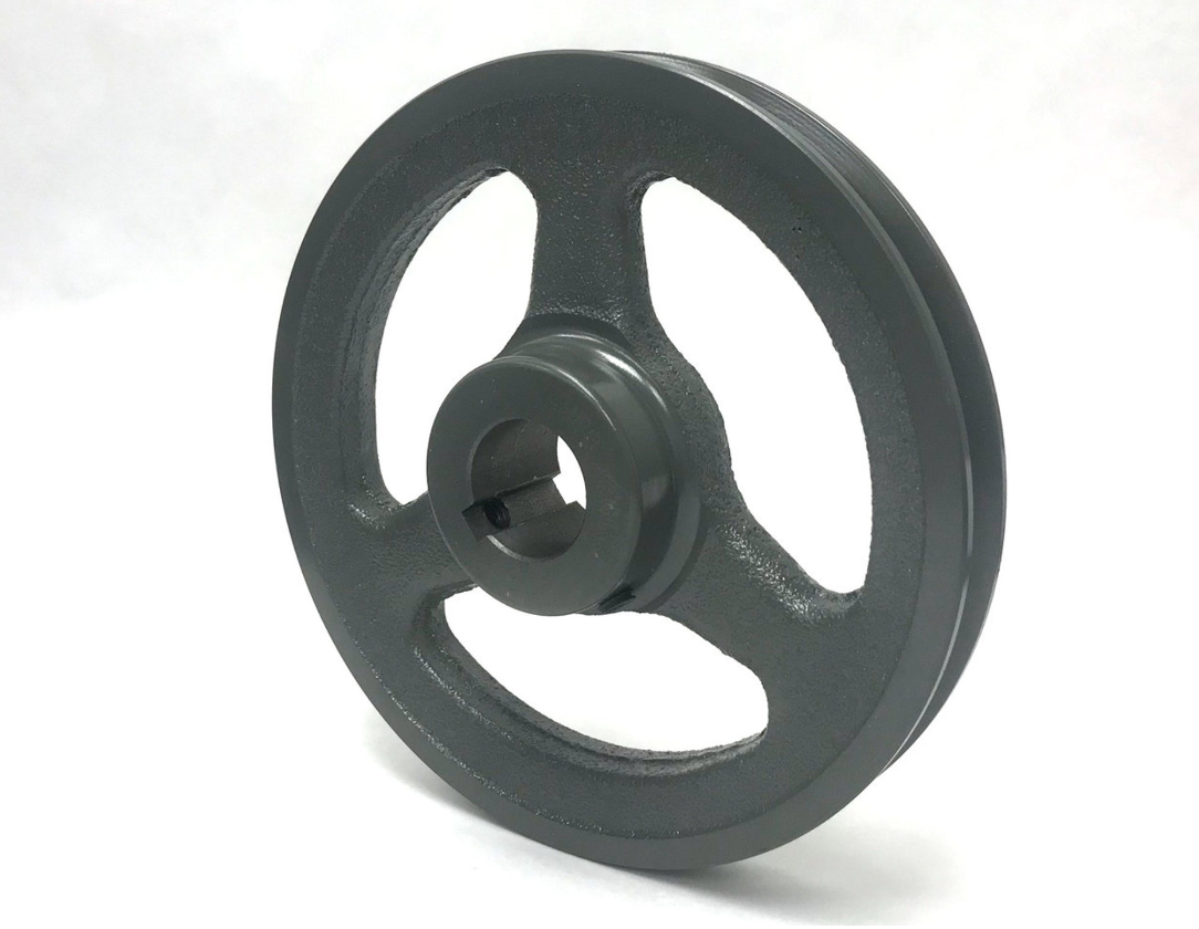 A close up of a gray iron pulley on a white surface
