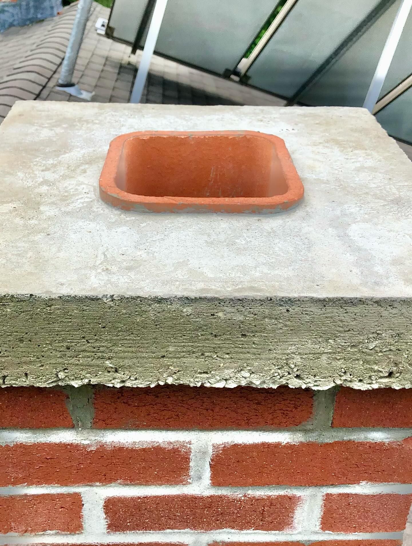 Brick chimney with a concrete cap and terracotta flue.