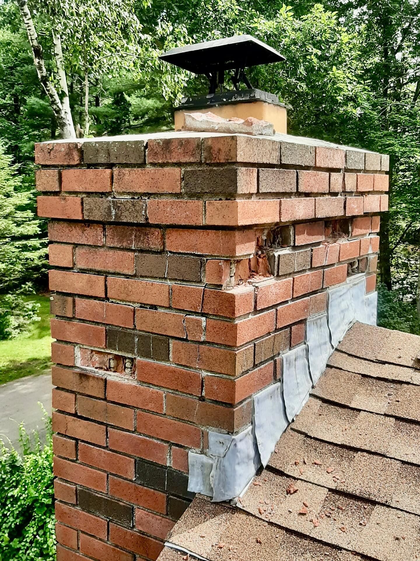 Brick chimney with visible damage and flashing around the roof.