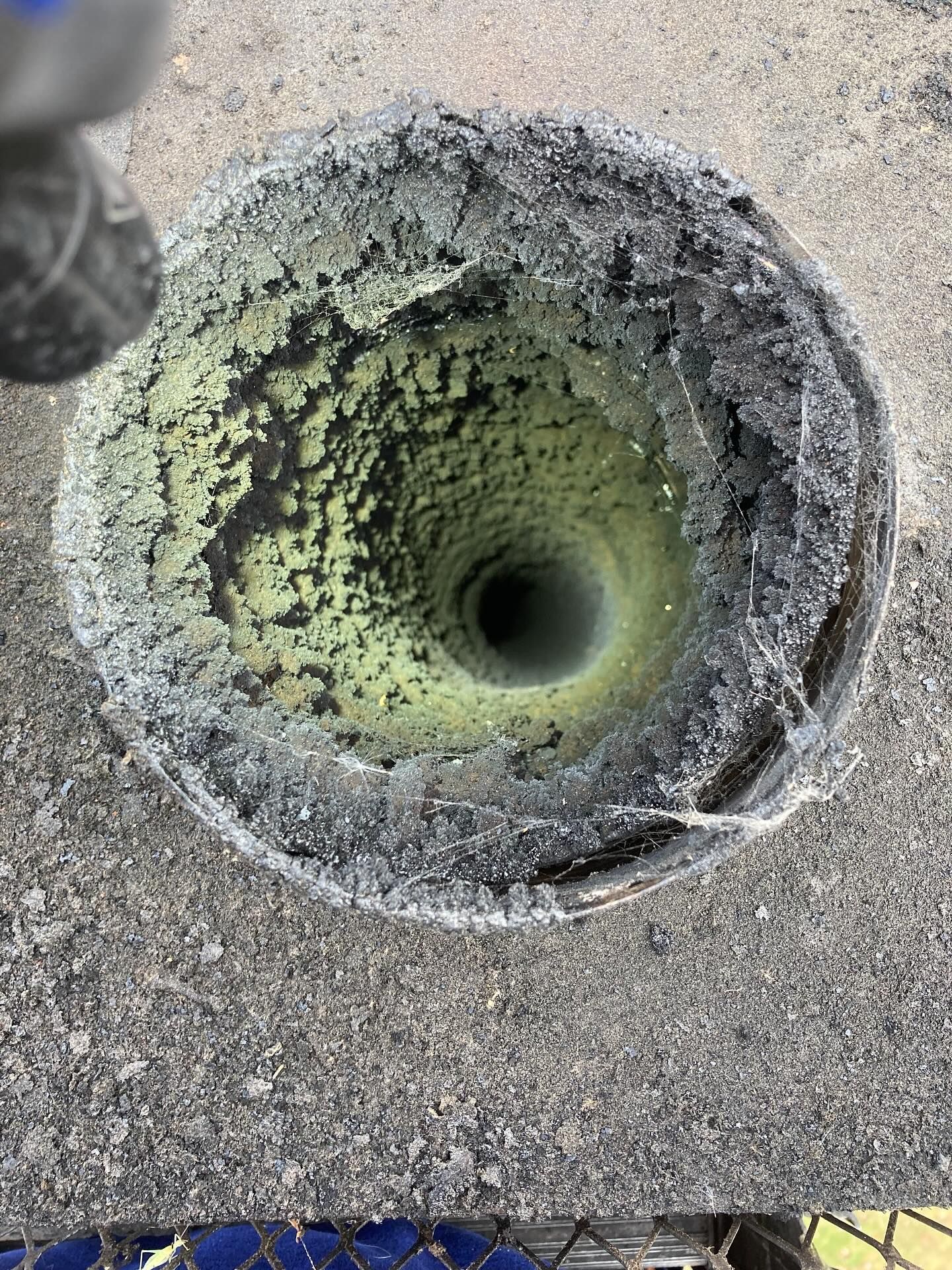 Looking down into a cylindrical, weathered pipe, showing interior layers of grime and discoloration.