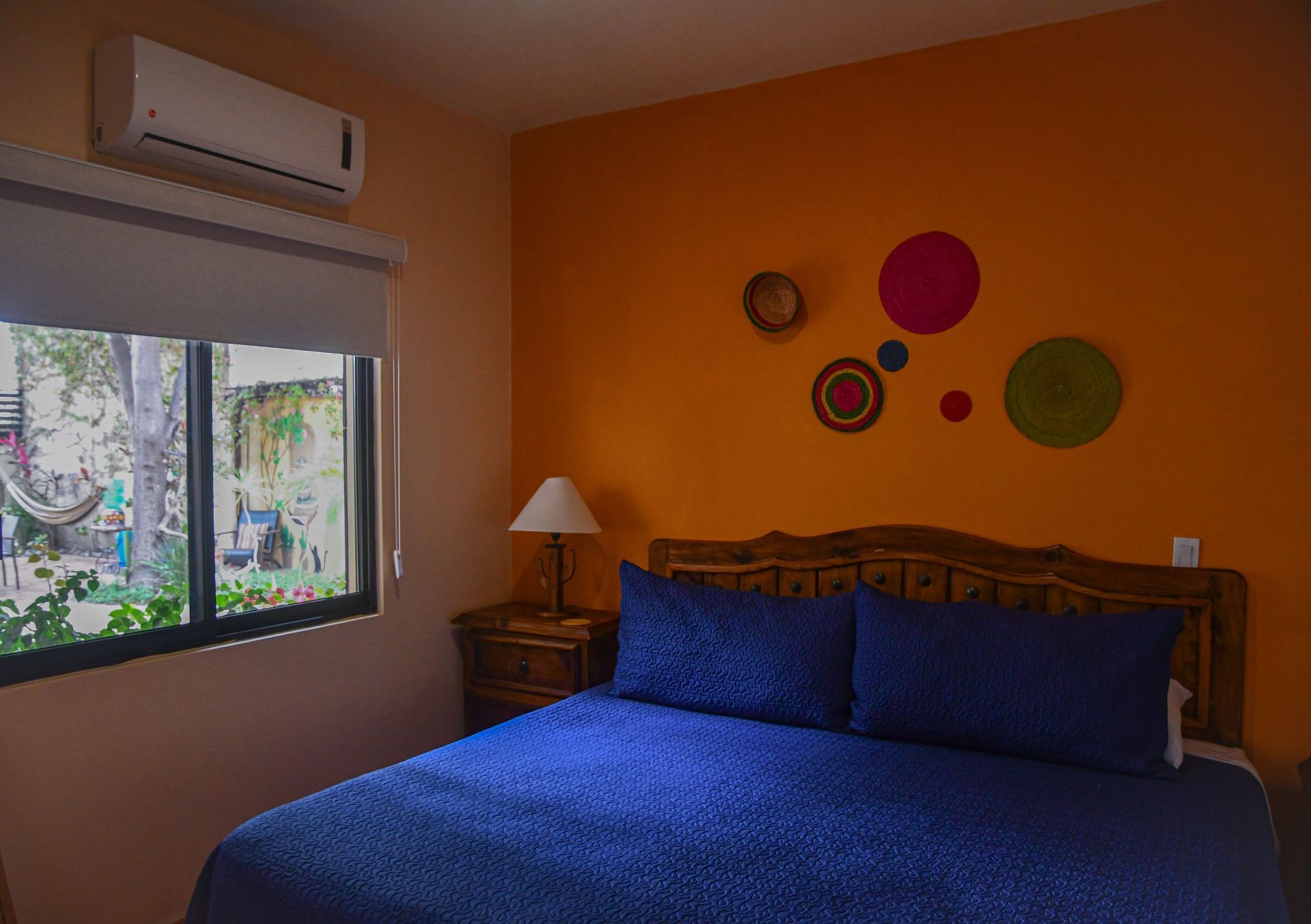 A bedroom with a bed , nightstand , window and air conditioner.