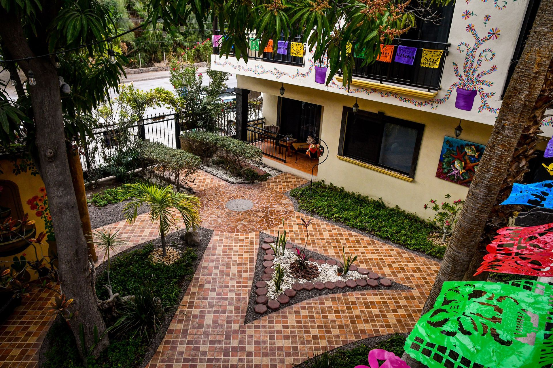 An aerial view of a house with a brick walkway surrounded by trees and flowers.