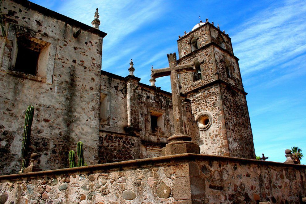 A large stone building with a cross in front of it