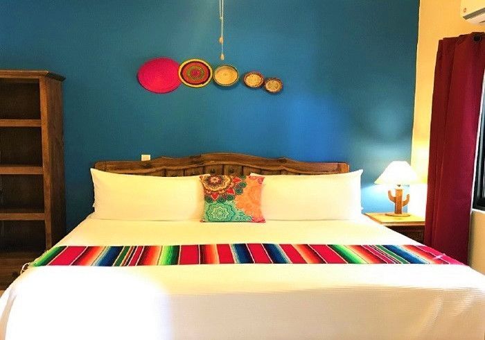A bed with a colorful blanket on it in a room with a blue wall
