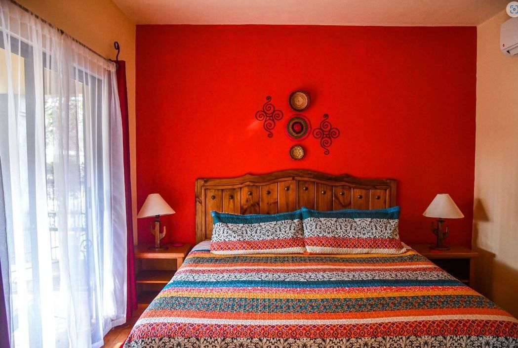A bedroom with a bed , lamps and a red wall.