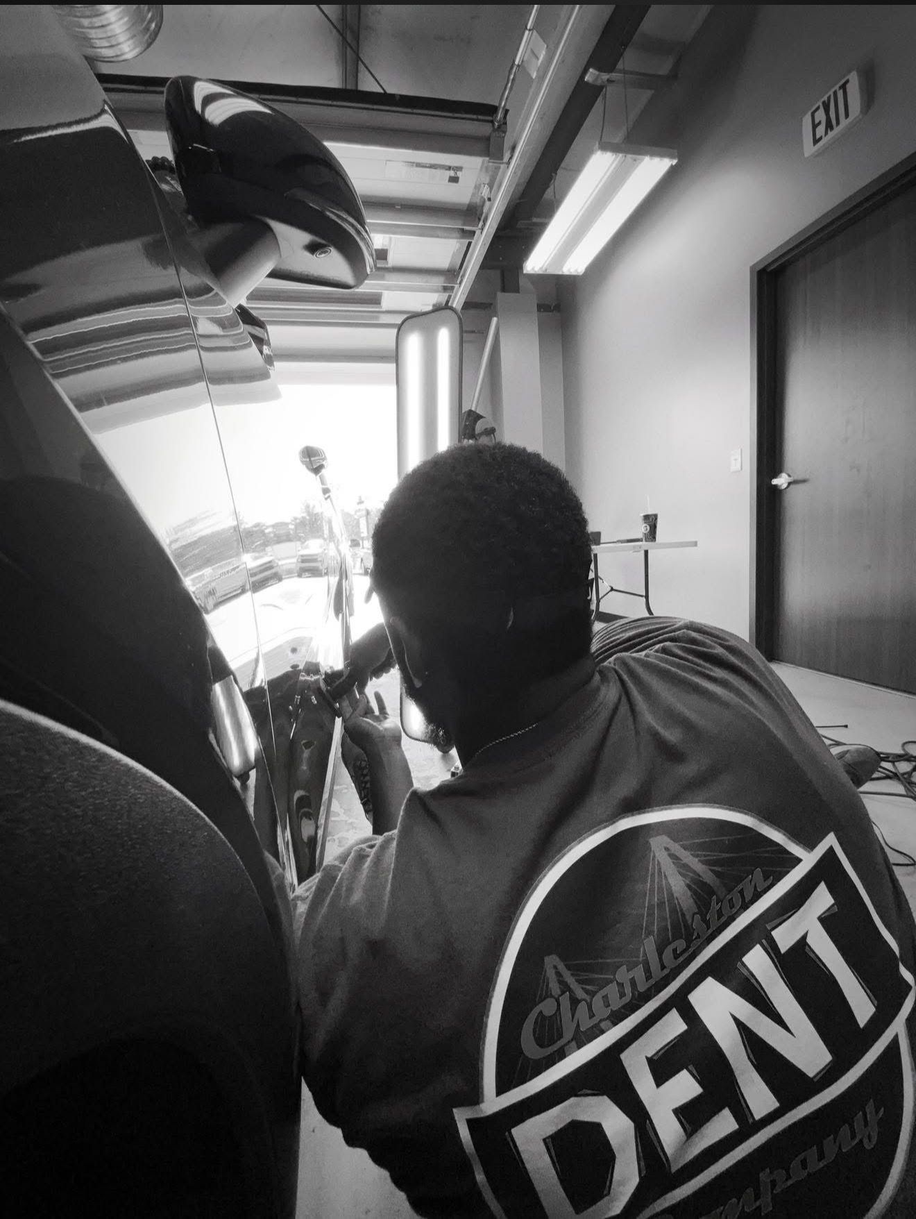 A Charleston Dent Company technician performing paintless dent repair on the lower portion of a car door using the glue pulling technique. 
