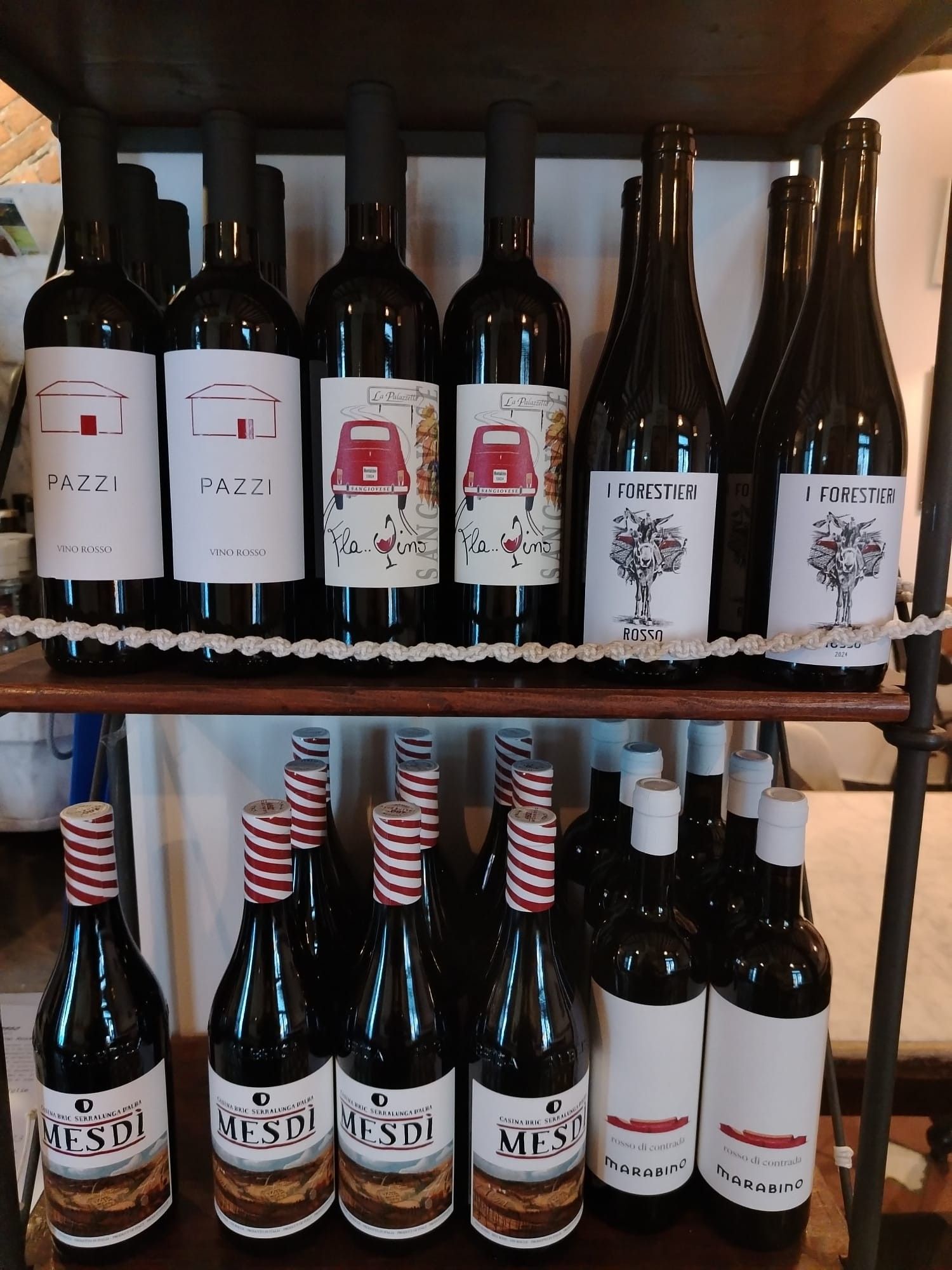 Bottiglie di vino sugli scaffali. Diversi tipi di bottiglie con etichette diverse e alcune con tappi a strisce.