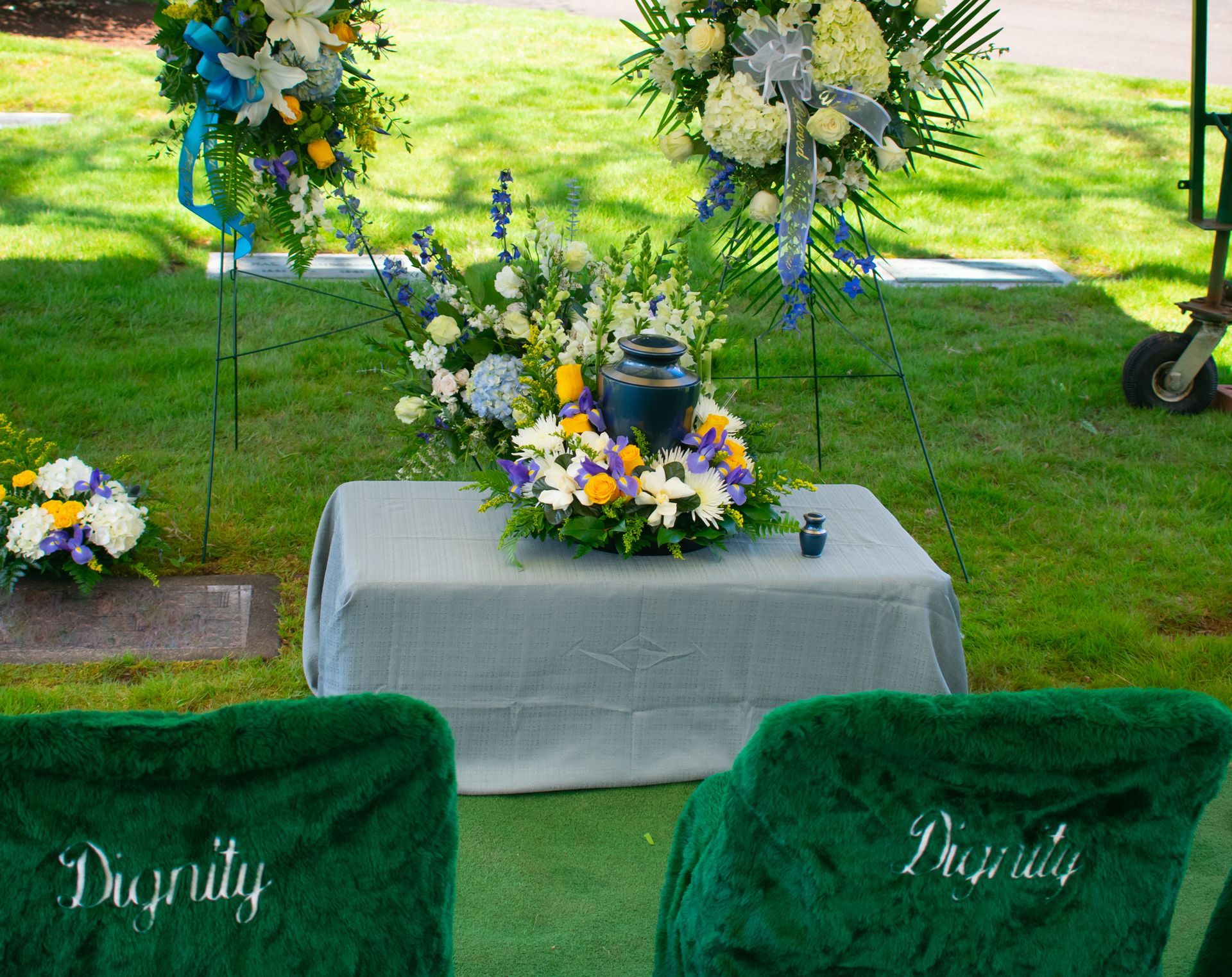 Funeral service: Urn on a table with floral arrangements, two chairs with