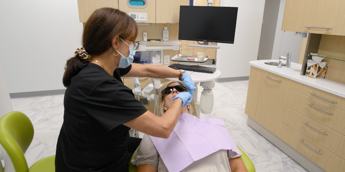 Dentist examining a patient's teeth in a dental office.