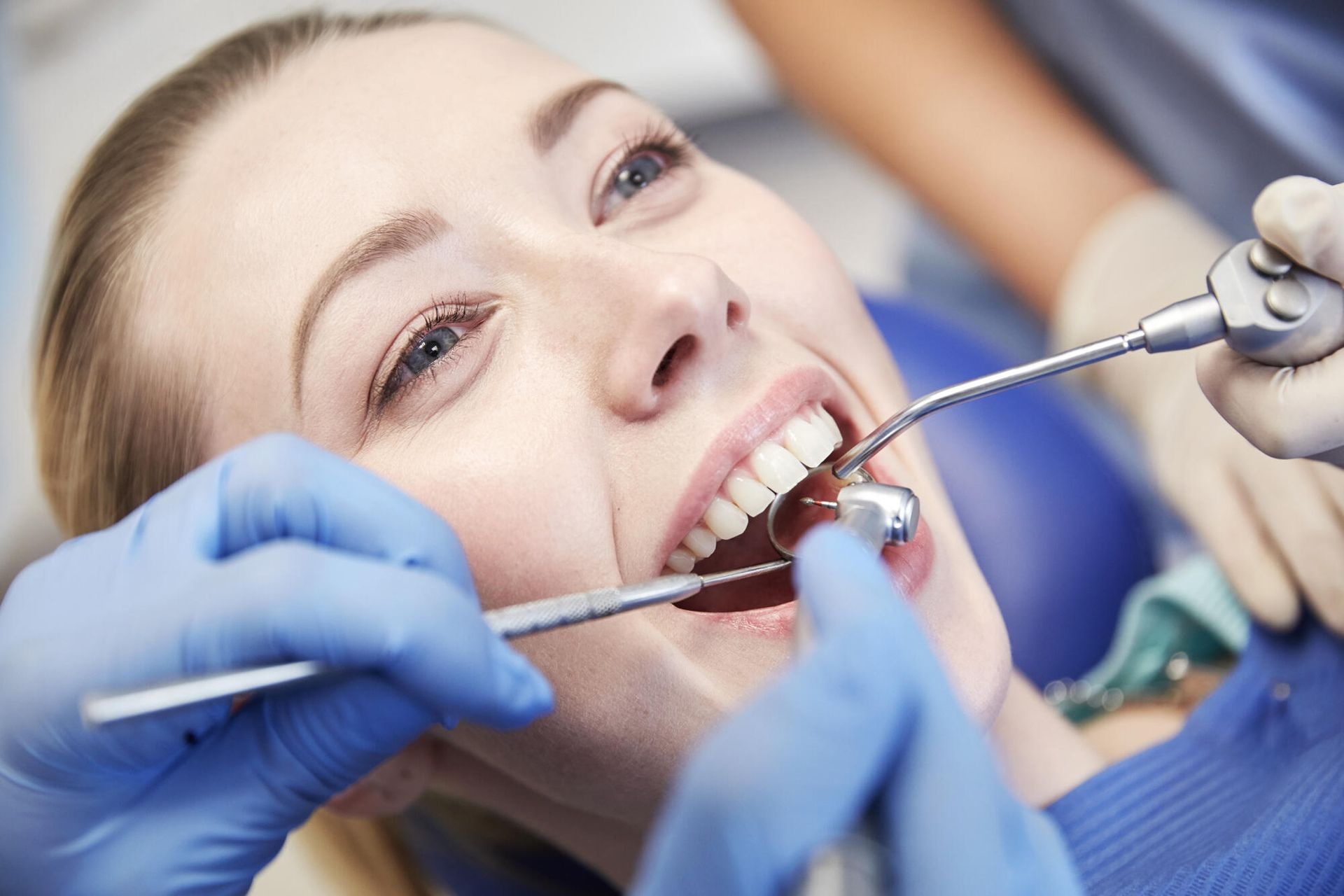 Dentist examining patient’s teeth with mirror and scaler in a dental office