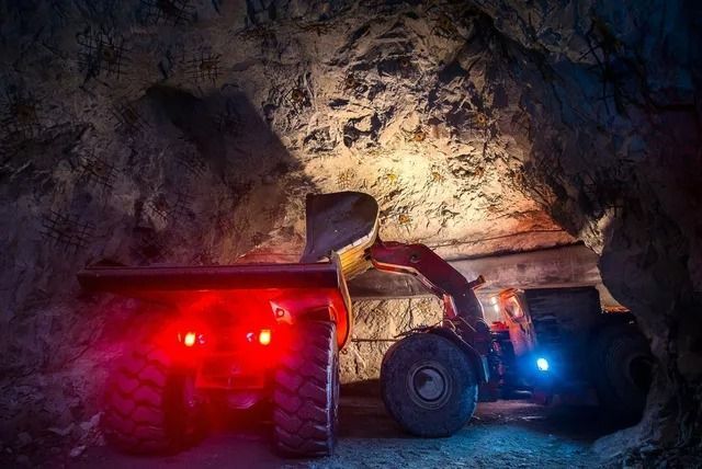 A Loader Filling a Mining Truck With Material Inside a Dark Cavern — Secure Mine Solutions in Port Ryan, QLD