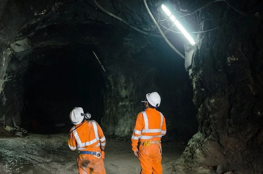 Two Workers in Orange Coveralls and Hard Hats Inspect a Dark Tunnel — Secure Mine Solutions in Port Ryan, QLD
