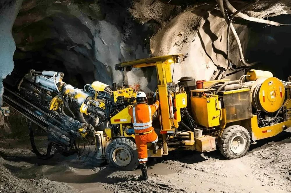 Worker in Orange Safety Gear Operates Yellow Drilling Machine — Secure Mine Solutions in Port Ryan, QLD