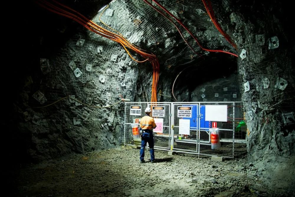 Person in Hard Hat Examines Safety Boards in a Dark, Underground Tunnel — Secure Mine Solutions in Port Ryan, QLD