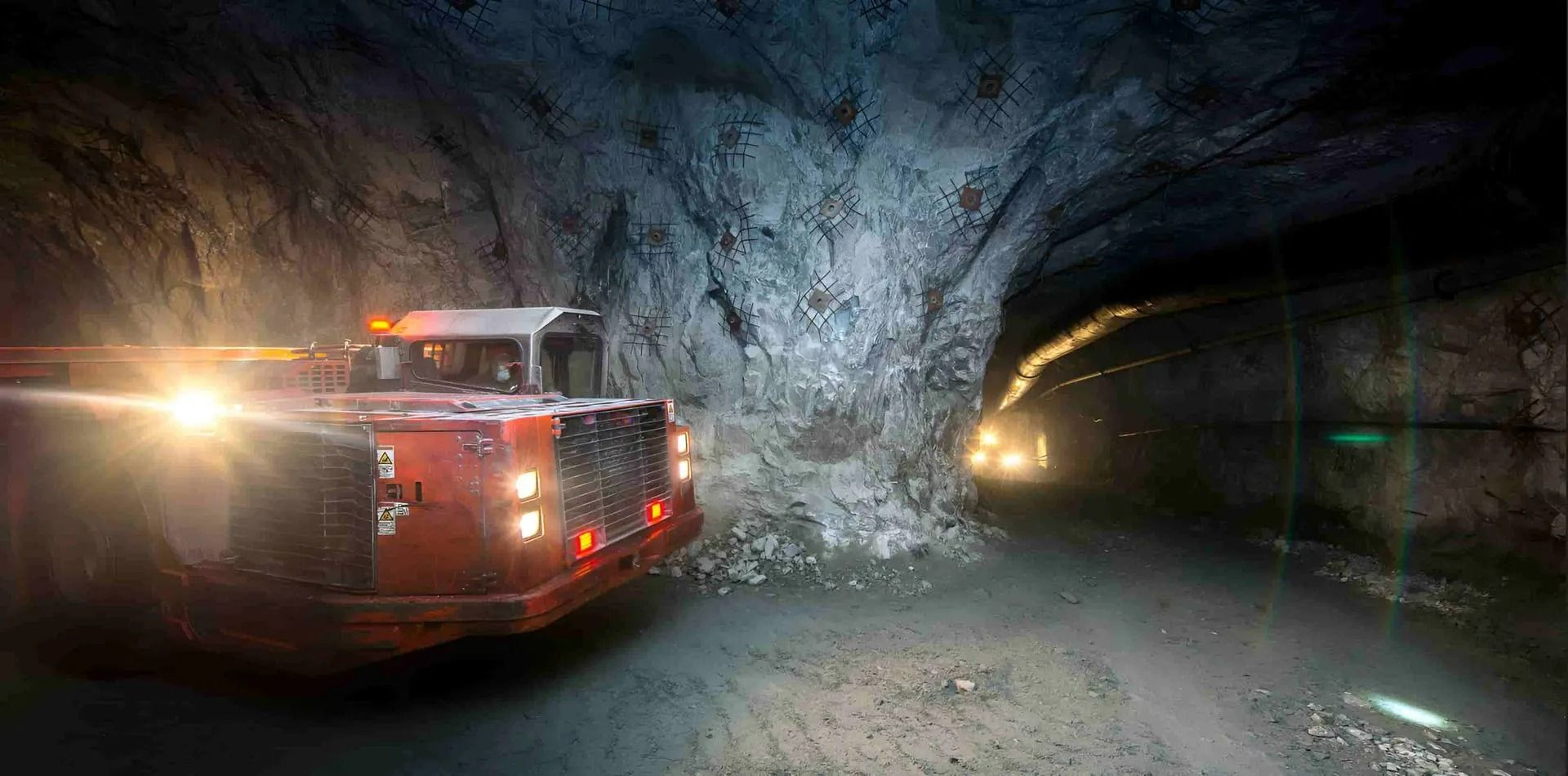 An Orange Mining Truck in a Dark, Rocky Tunnel — Secure Mine Solutions in Port Ryan, QLD