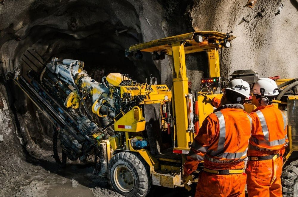 Two Workers Observe a Yellow Drilling Machine in a Tunnel — Secure Mine Solutions in Port Ryan, QLD