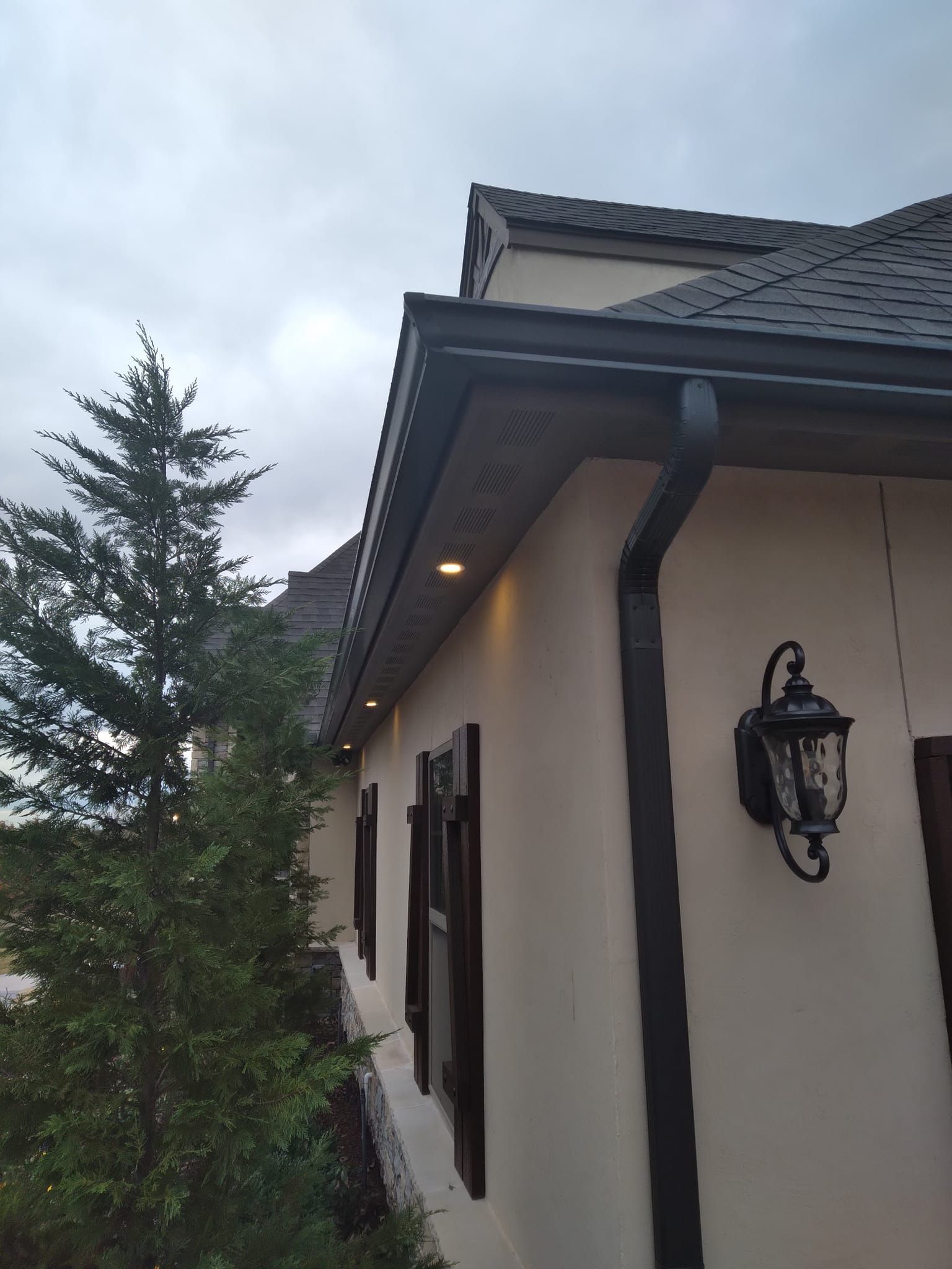 A house with a gutter and a lamp on the side of it.