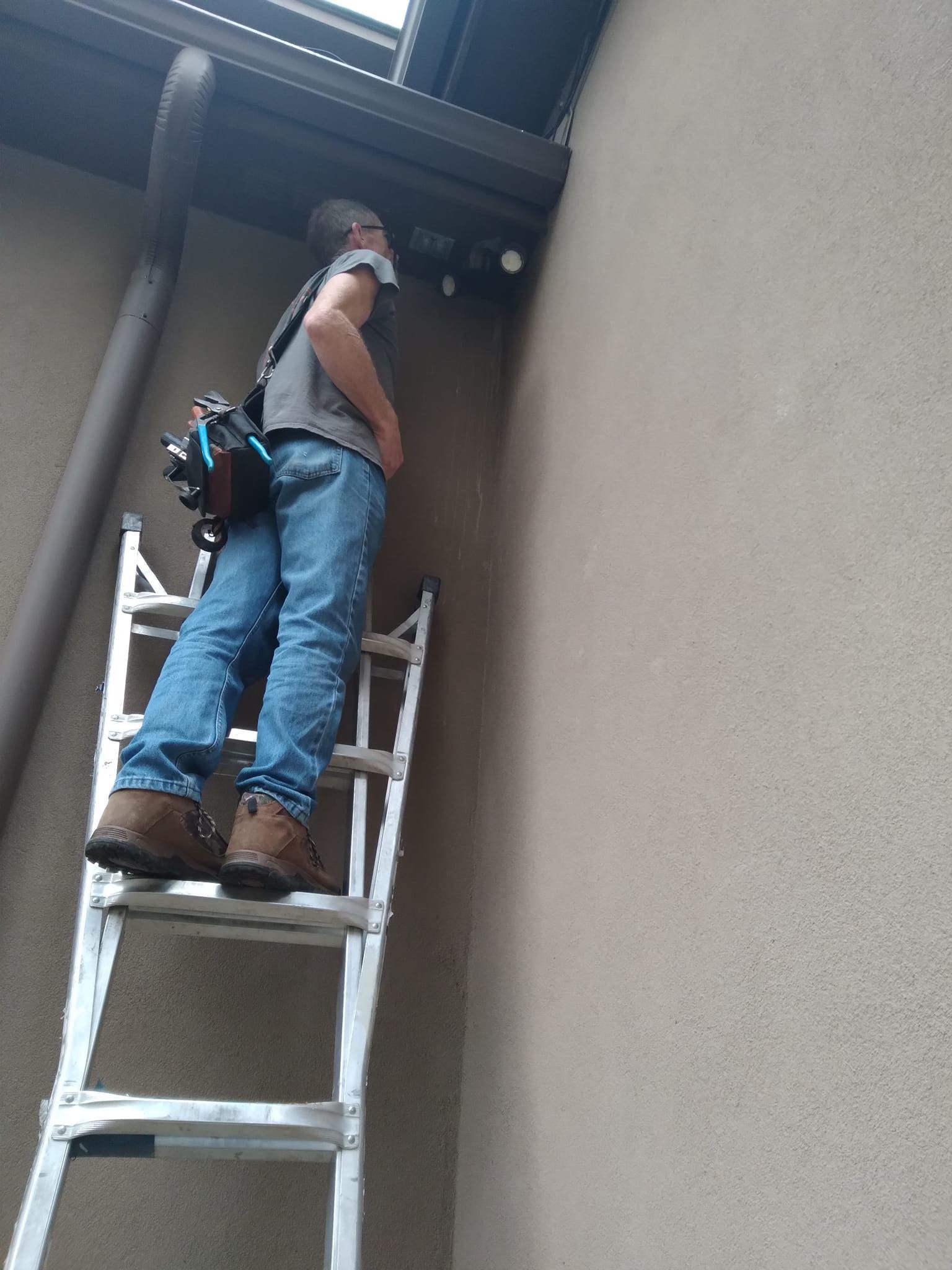A man is standing on a ladder next to a wall.