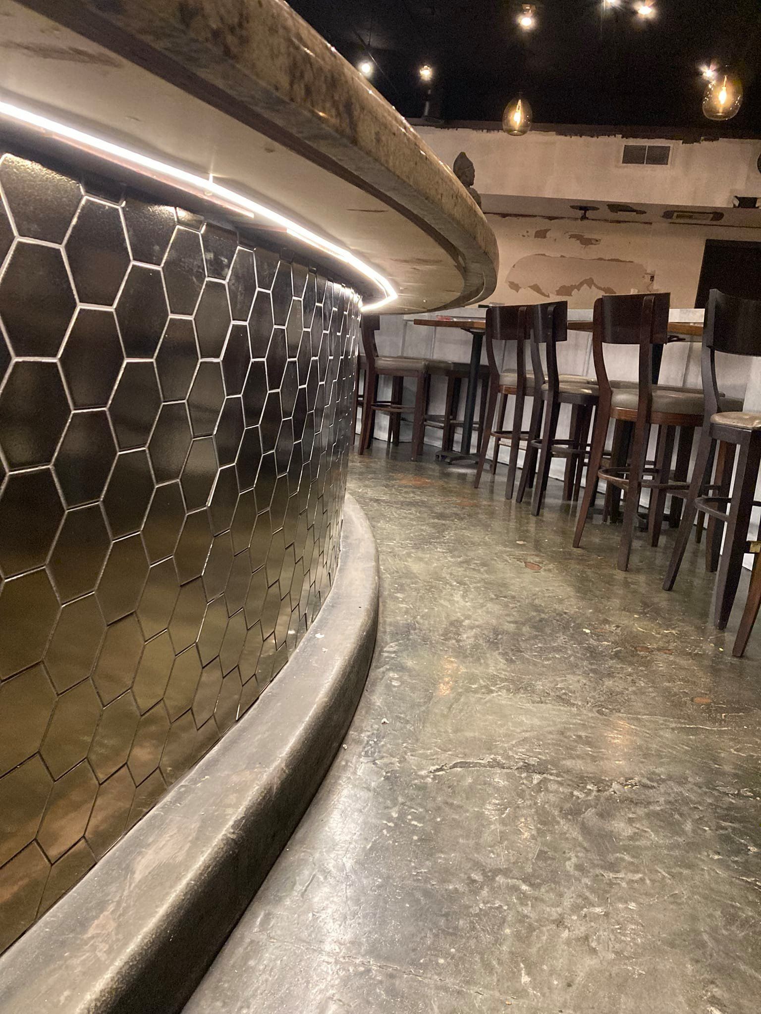 A row of stools are lined up in front of a bar in a restaurant.