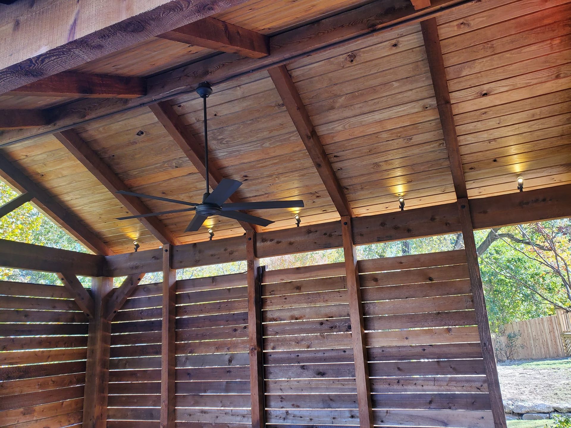 A ceiling fan is hanging from the ceiling of a wooden structure.