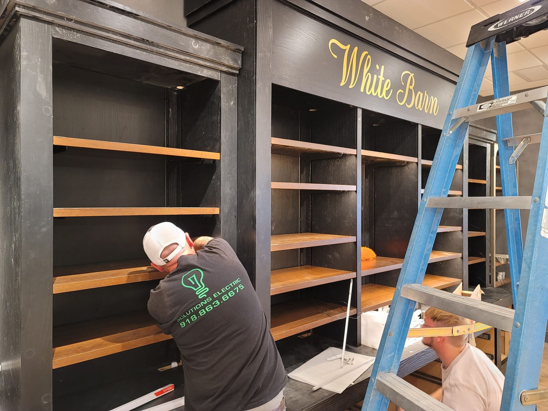 Two men are working on shelves in a store.