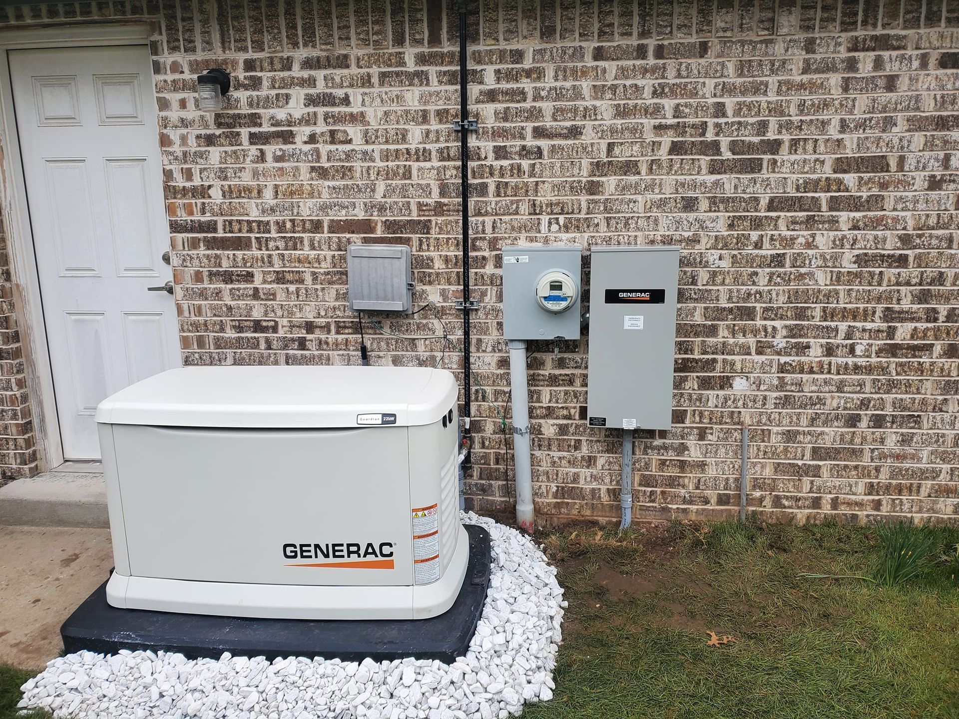 A generator is sitting in front of a brick building.
