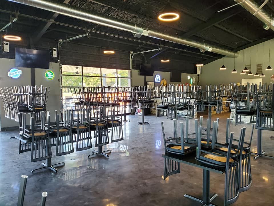 A large room with tables and chairs stacked on top of each other.